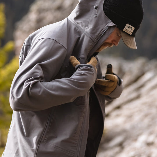 A backcountry hunter putting on the Stone Glacier De Havilland Jacket while on the mountain.